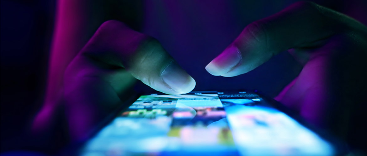 Fotorealistische Nahaufnahme einer Smartphone-Nutzung mit leuchtendem Display in dunkler Umgebung – Symbol für Urheberrecht, Medienrecht, digitale Inhalte, Social Media und Online-Kommunikation.