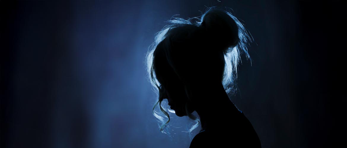Dramatisch beleuchtete Silhouette einer Person vor dunklem Hintergrund, Symbolik für Opferschutz, Anonymität, Sicherheit und Sensibilisierung.