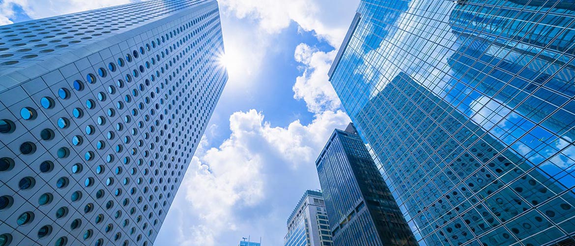 Moderne Hochhausfassaden aus Glas und Stahl mit Blick nach oben in den Himmel – Symbol für Wirtschaftsrecht, Urheberrecht, Medienrecht, Unternehmen, Digitalisierung und Compliance.