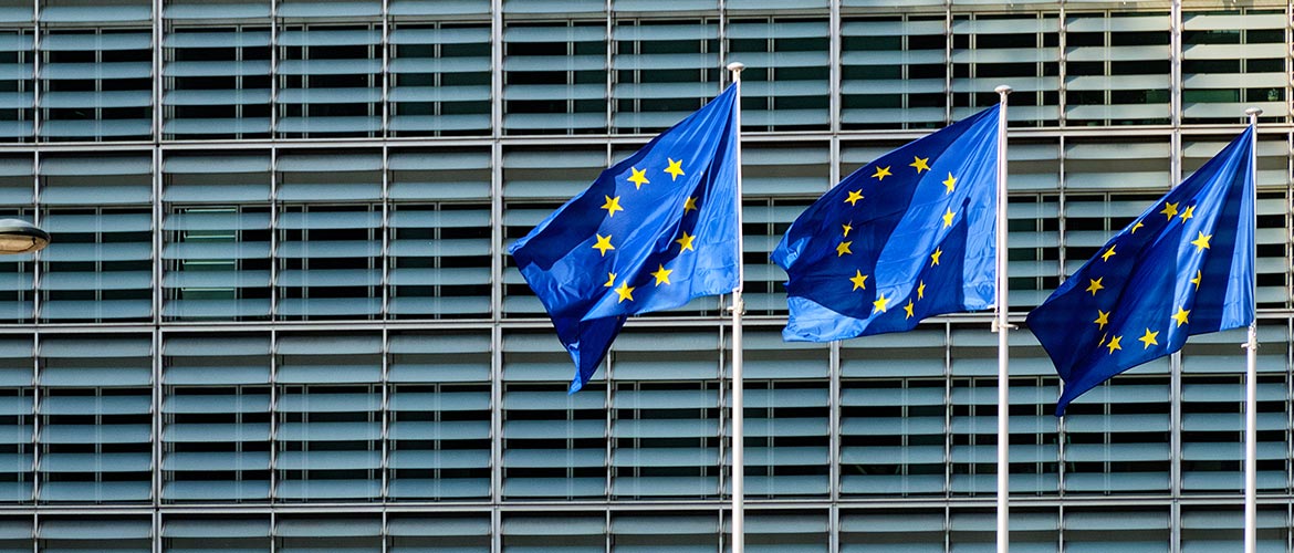 EU-Flaggen vor moderner Glasfassade eines Verwaltungsgebäudes, Symbol für Europäische Union, EU-Förderung, EU-Hilfen, Politik, Wirtschaft, Europa, Institutionen.
