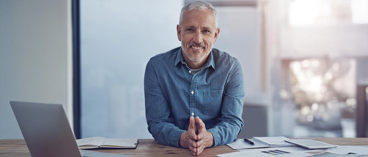 Person am Schreibtisch im modernen Büro, Laptop, Unterlagen und Notizbuch, professionelles Arbeitsumfeld, Business, Arbeitsplatz, Meeting-Vorbereitung.