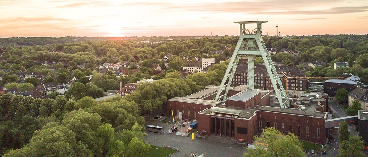 Luftaufnahme des Bergbaumuseums Bochum bei Sonnenuntergang, Förderturm, Ruhrgebiet, Industriegeschichte, grüne Stadtlandschaft.