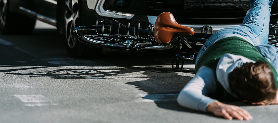 Fotorealistische Abbildung eines Verkehrsunfalls mit Fahrrad und Pkw auf der Straße, Person am Boden, Verkehrsrecht, Haftung, Schadensersatz, Unfallanalyse, Straßenverkehr.
