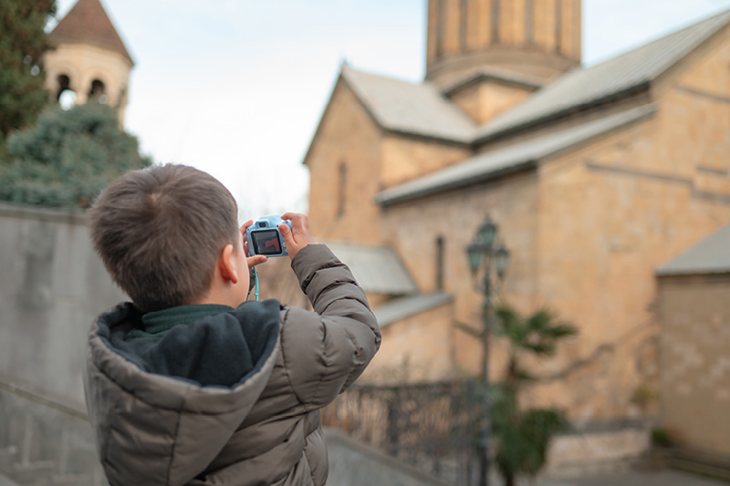 Ein Junge steht vor einer Kirche und fotografiert diese