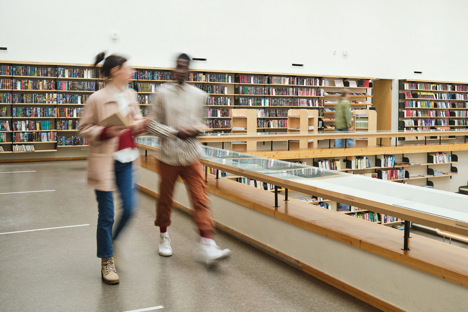 Zwei Personen bewegen sich in einer Bibliothek
