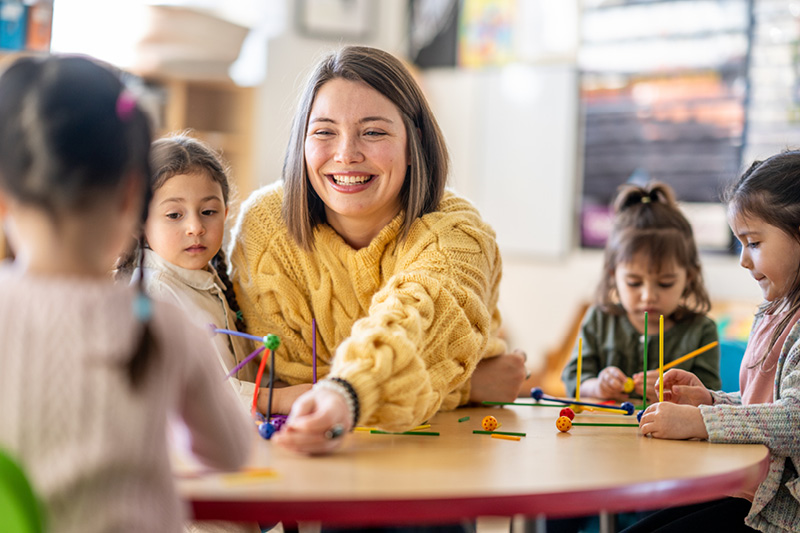 Eine Fachkraft mit spielenden Kindern in der Kita