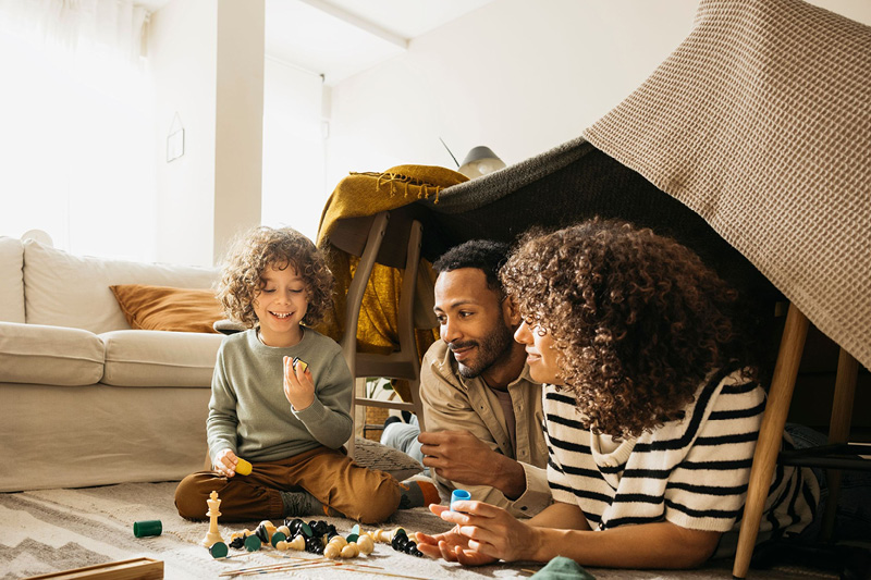 Ein Kind spielt im Wohnzimmer mit seinen Eltern
