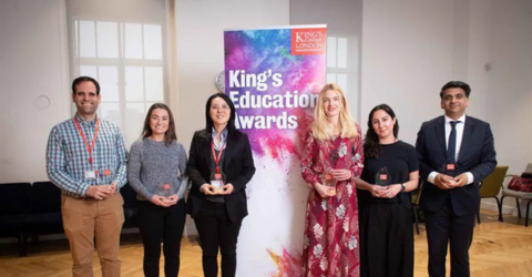 Students and staff are taking a photo in front of a stand that says 'King's Education Awards'.