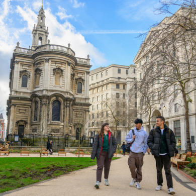 Three students walking on the pedestrianised Strand with St Mary le Strand church in the background