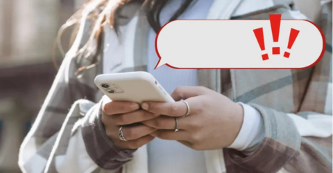 A person is using their phone with a pop-up  an animated exclamation mark appears