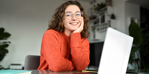 Lächende Frau sitzt vor Laptop