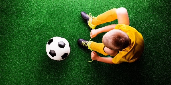 Kind, das sich die Fussballschuhezuschnürt