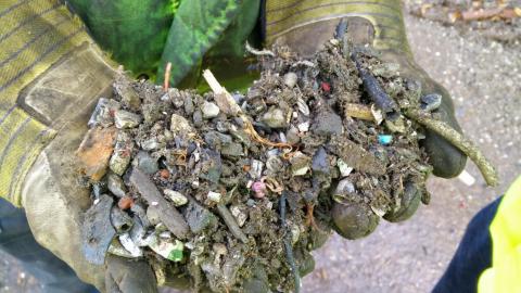 Two gloved hands holding a mixture of parts