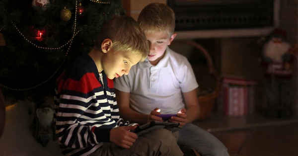 Kinder unter dem Weihnachtsbaum mit Smartphones in der Hand