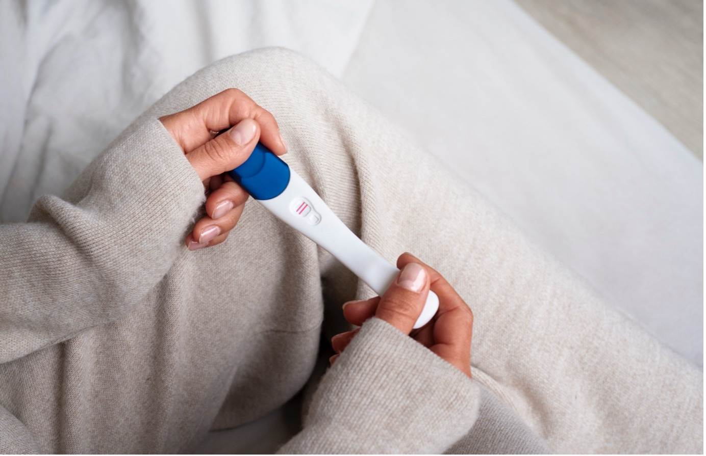 Mujer con test de embarazo en las manos tras una fecundación in vitro