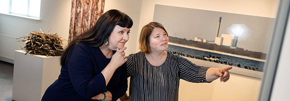 Kaksi henkilöä katselee museossa taideteoksia.