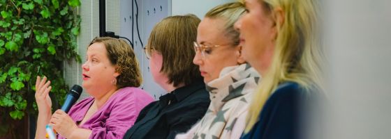 Neljä panelistia rivissä, vasemmalla puhujalla mikrofoni.