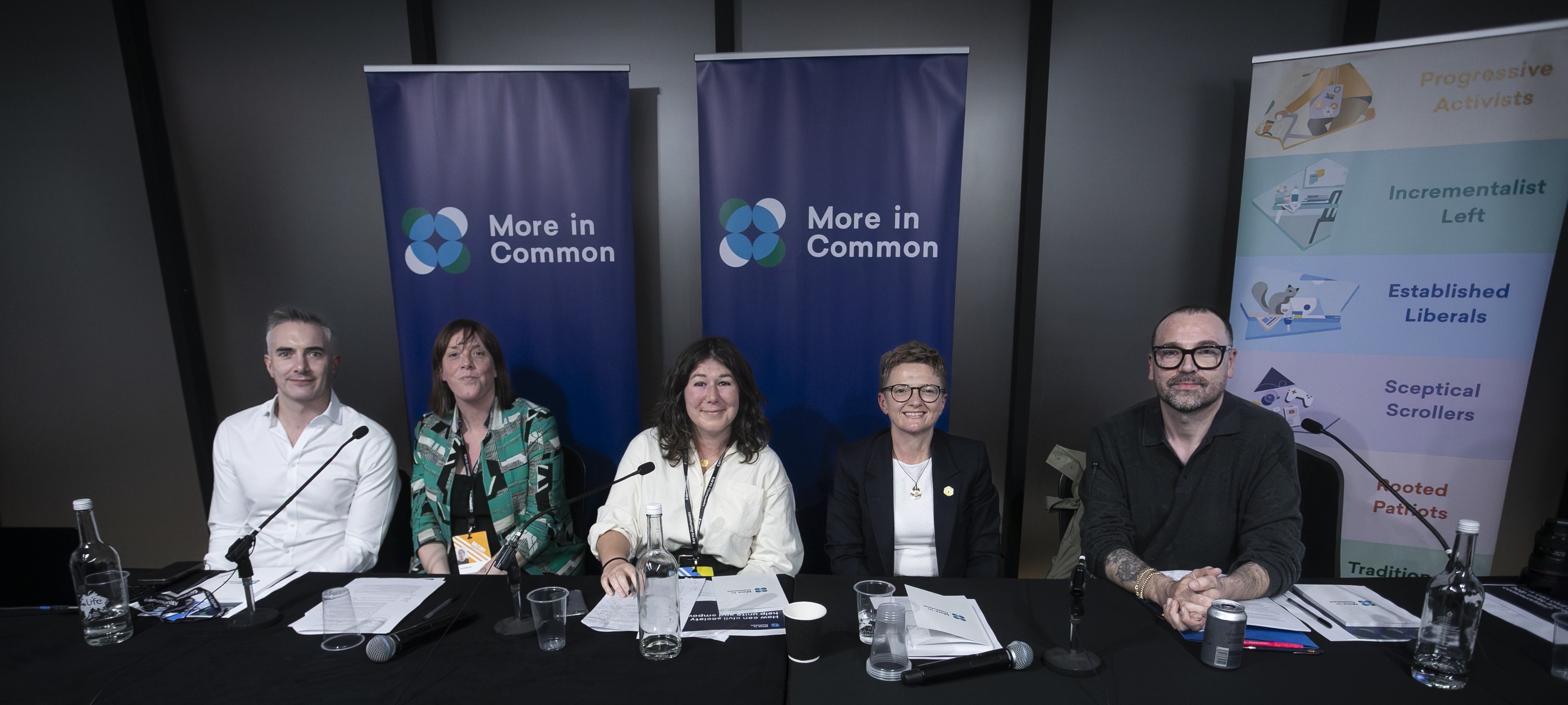 Five speakers seated behind microphones at NCVO and More in Common UK’s Labour Party Conference fringe event. The event’s line-up included Jess Phillips MP, Bev Craig OBE, Melanie Ward MP, Luke Tryl and Leigh Brimicombe, with chair Anoosh Chakelian. More in Common banners stand behind the table.