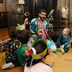 Kinderen zitten in een groepje op de grond in het museum en krijgen een rondleiding