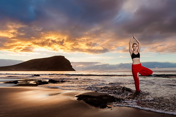 Girl doing yoga at sunset on La Tejita de Granadilla de Abona beach in Tenerife, Canary Islands