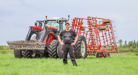 A farmer standing on front of his tractor in a field