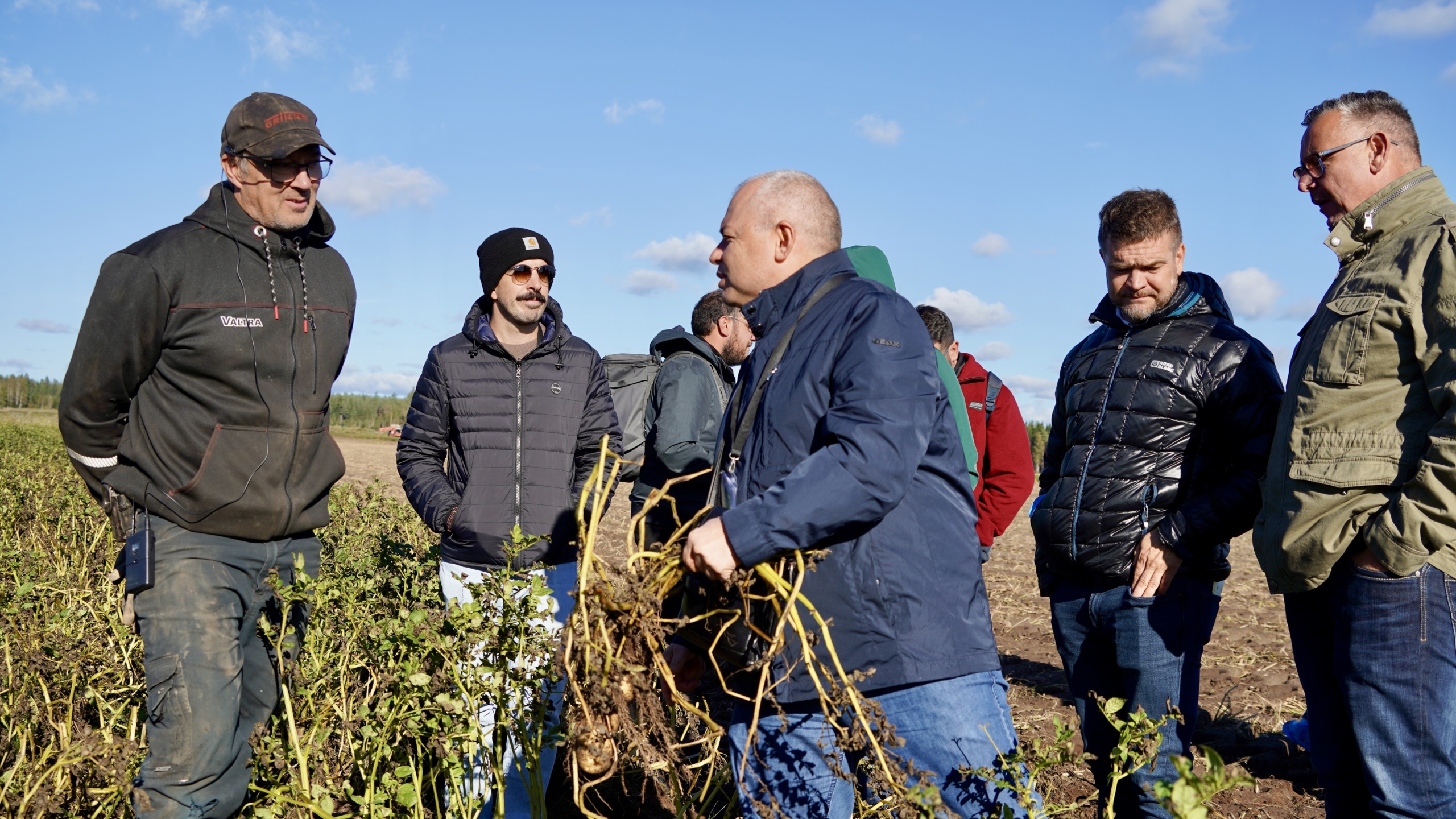 Henkilöitä pellon reunalla.