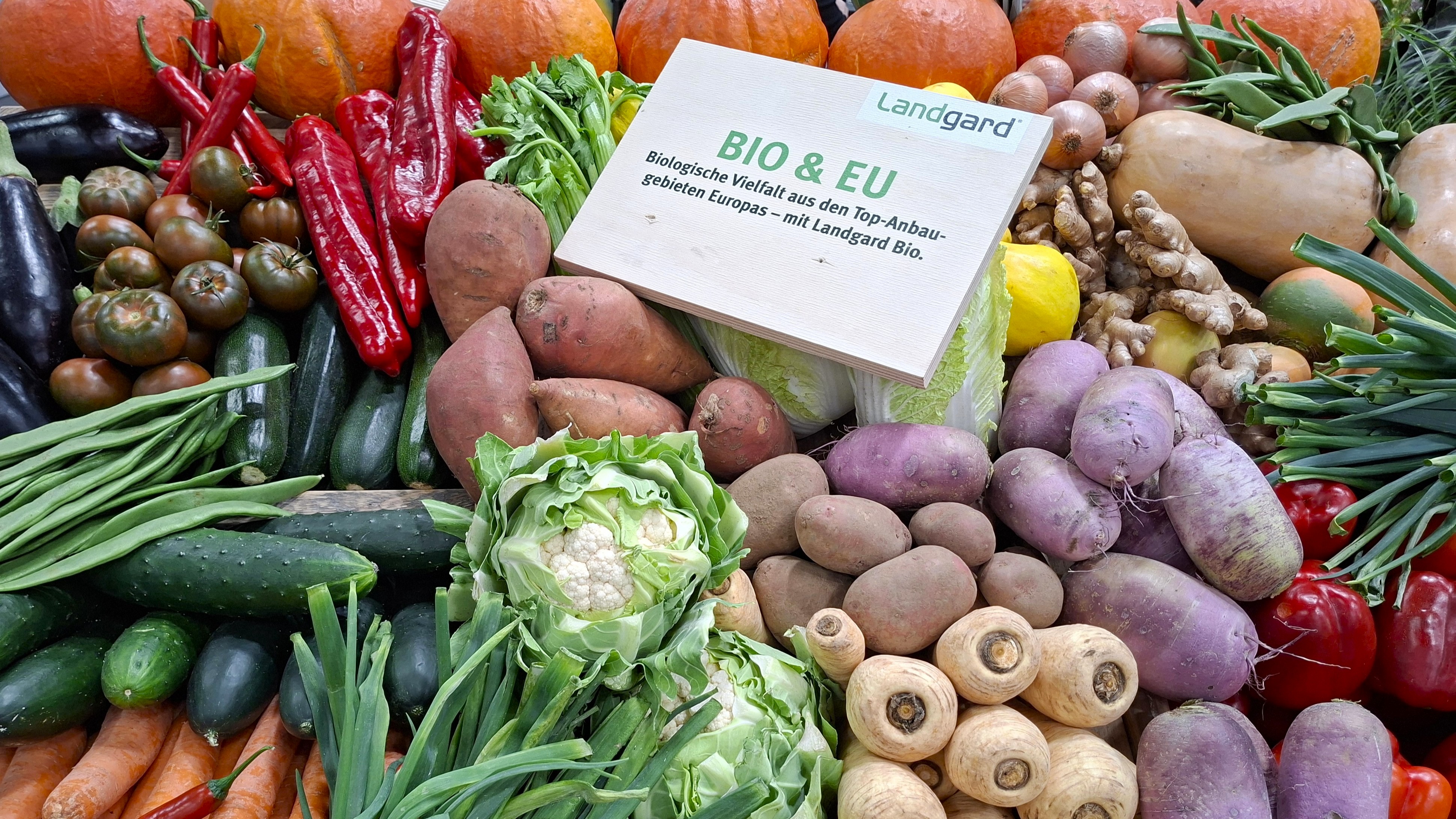 Kasa kasviksia toistensa päällä ja puinen saksankielinen kyltti.