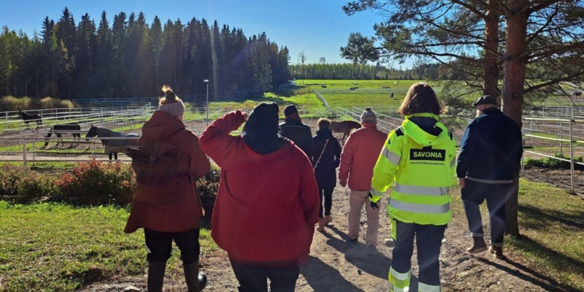 Henkilöitä ulkona hevosaitauksen vieressä.