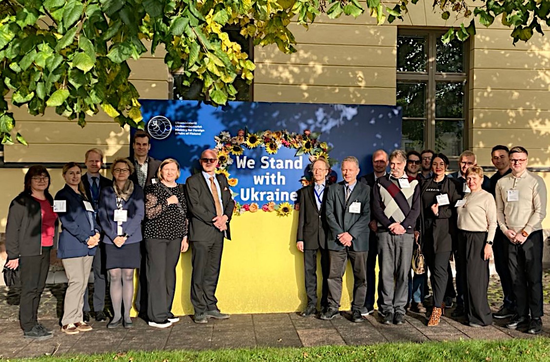 Ihmisiä seisomassa "We stand with Ukraine" -tekstin edessä.