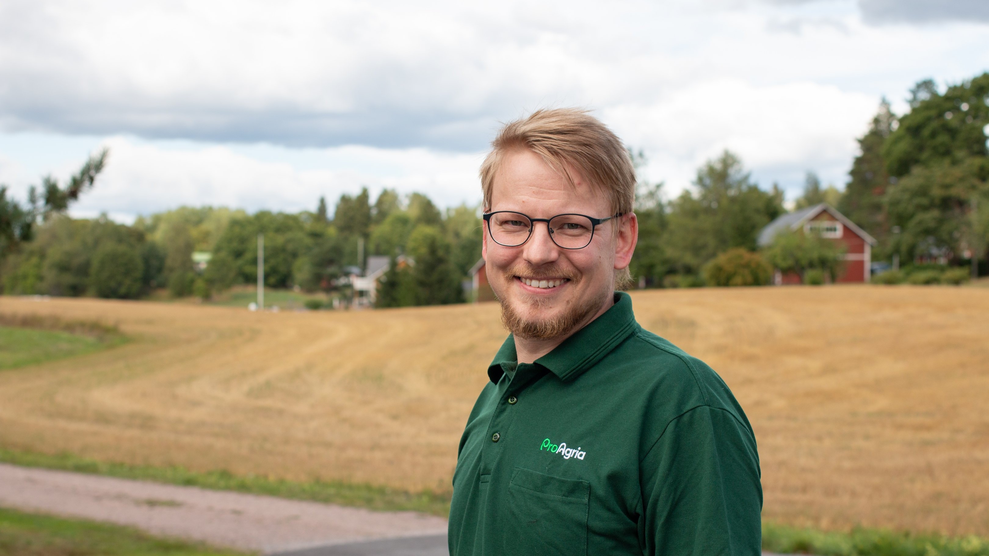 Kasvokuva, jonka takana näkyy peltoa.