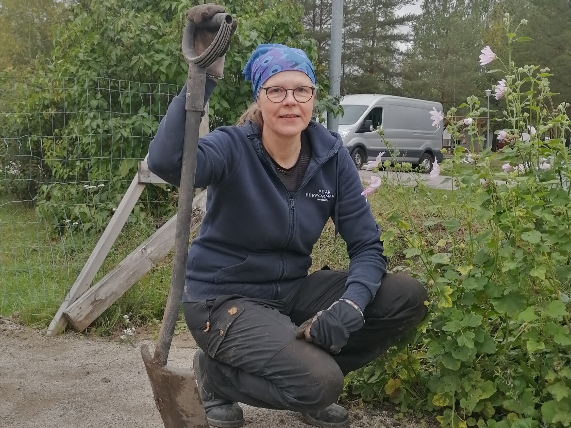 Researcher kneeling down and leaning on shovel