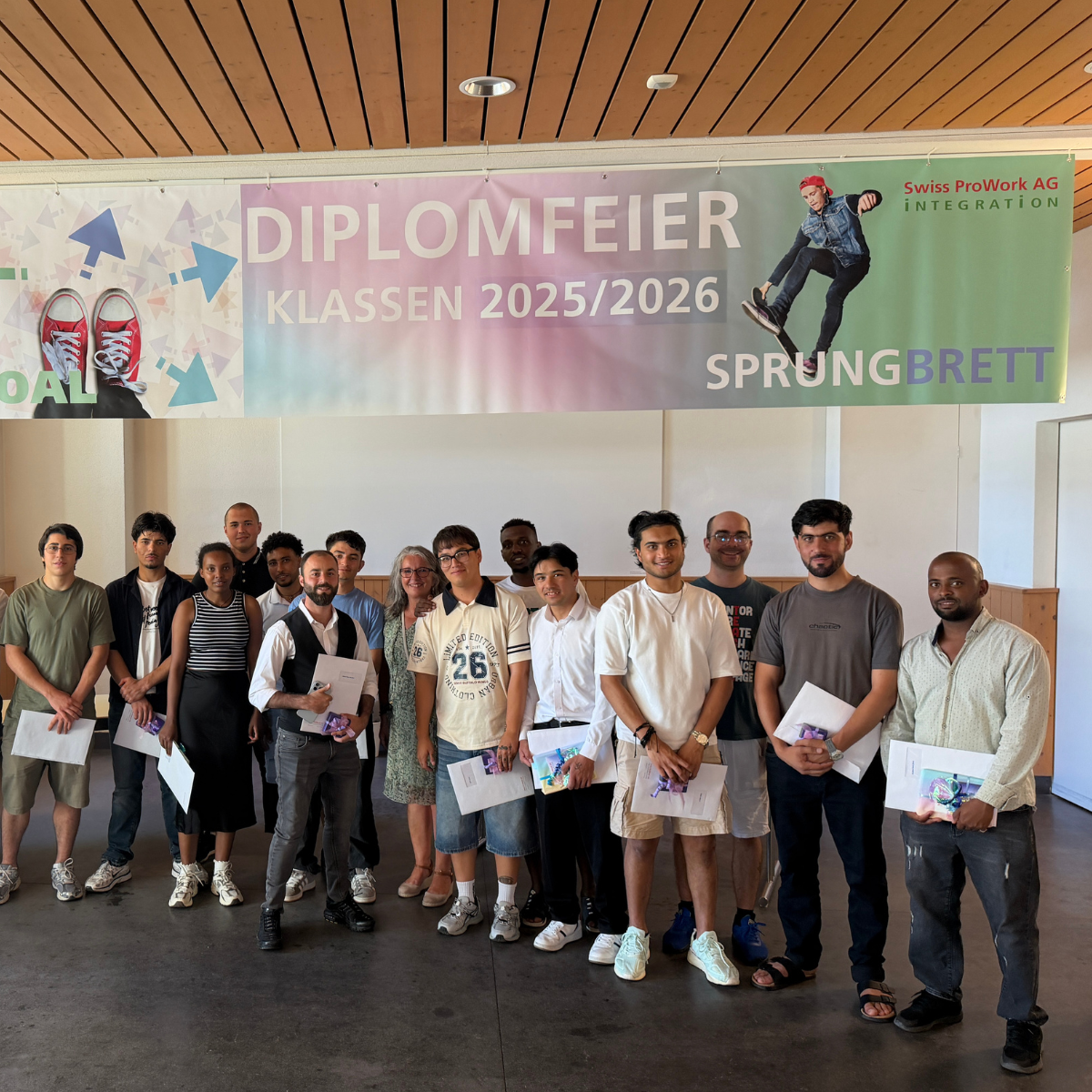 Absolventinnen und Absolventen mit ihren Diplomen vor dem Banner der Diplomfeier