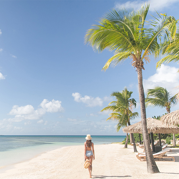 A guest strolls along the Jumby Bay Beach