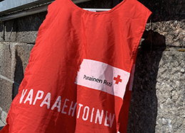 Punaisen Ristin vapaaehtoisliivi liehuu ulkoilmassa henkariin ripustettuna.