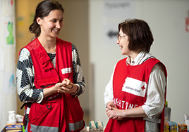 Kaksi henkilöä, joilla on Punaisen Ristin liivit yllään, katsovat toisiinsa. 