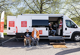 retkeilyauto sivuovi avoinna, jonka sisällä ja edessä istumassa tuoleilla henkilöitä.