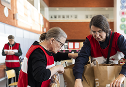 Kaksi henkilöä ottamassa tavaroita paperikasseista.