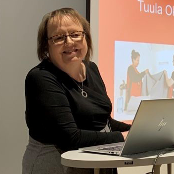 Hymyilevä henkilö kannettava tietokone pöydällä edessään.
