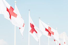 Punaisen Ristin lippuja liehumassa sinistä taivasta vasten.