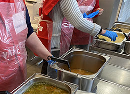 Henkilöitä, joilla on Punaisen Ristin vapaaehtoisliivi jakamassa ruokaa, 