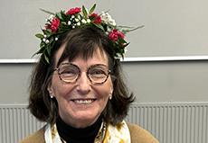 Hymyilevä henkilö kukkaseppele päässään.