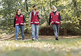 Kolme Punaisen Ristin vapaaehtoista kävelemässä ulkona luonnossa.