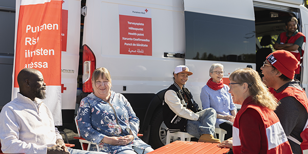 Ihmisiä istumassa valkoisen retkeilyauton edessä