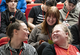 Hymyileviä henkilöitä istumassa auditoriossa.