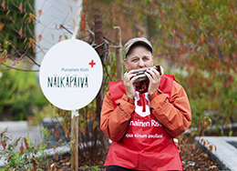 Punaisen Ristin Nälkäpäivä-kerääjä istuu ulkona ja soittaa huuliharppua.