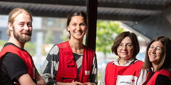 Neljä hymyilevää henkilöä rinnakkain.