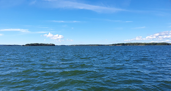 Meri ja kauempana saaria, joissa havupuita.