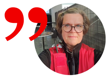 Punainen liivi yllään oleva henkilö katse kohti kameraa.