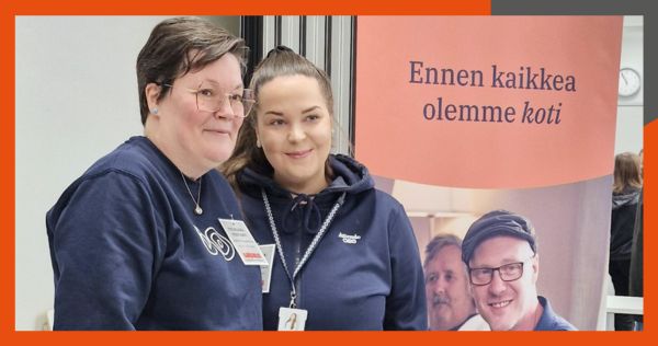 Kaksi hymyilevää naista sinisissä työvaatteissa.