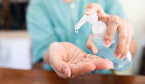 person in the background, hand disinfectant and hands in front